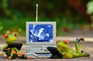 Logo Facebook in pc con due rane che usano smartphone | PostPickr