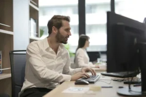 Impiegato seduto nella sua scrivania in ufficio, impegnato nell'ottimizzazione delle campagna pubblicitarie su Facebook | PostPickr