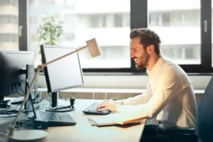Uomo seduto alla sua scrivania in ufficio mentre utilizza Linkedin Ads | PostPickr